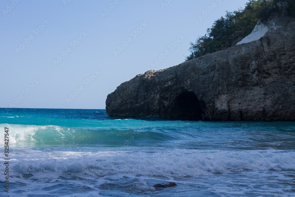 Caribbean sea, shore with a cave in the background. Blue sky. 'Grand Anse' region, Haiti