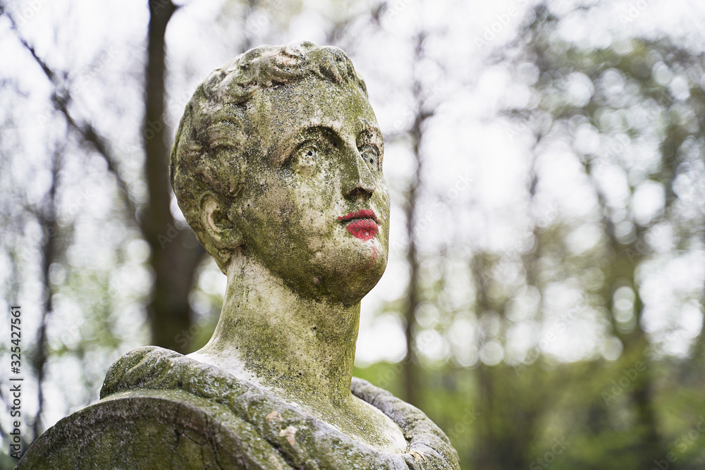 Old stone statue in Brussels public park with red painted colored lips with lipstick or paint Old stone statue in Brussels public park with red painted colored lips with lipstick or paint