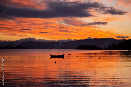 Boat moored at the bay, Sambaqui beach. Colorful orange and red clouds. Florianópolis, Santa Catarina / Brazil © hansdenis