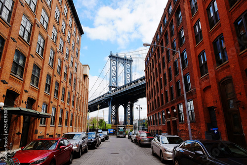 Tablou pe pânză Manhattan bridge seen from a red brick buildings in Brooklyn street in perspective, New York, USA