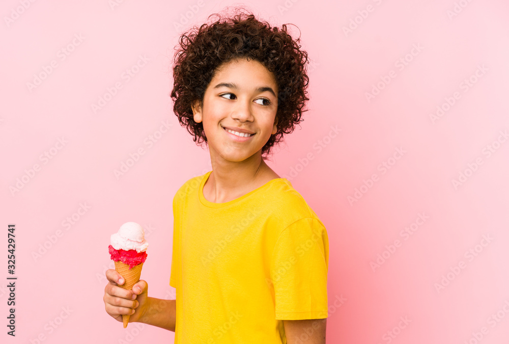 Kid boy holding an ice cream isolated looks aside smiling, cheerful and pleasant. Kid boy holding an ice cream isolated looks aside smiling, cheerful and pleasant.