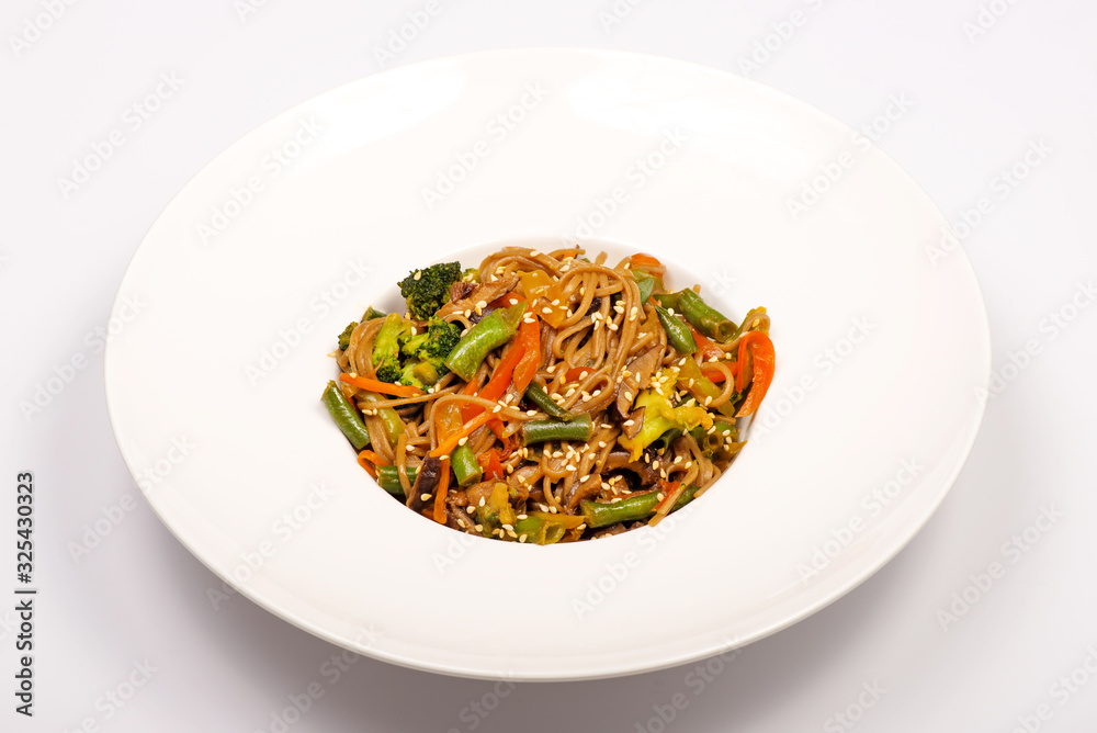 Buckwheat noodles with broccoli, green beans, sweet peppers, Asian-style sesame mushrooms. Vegetarian dish. in a white plate on a white background Buckwheat noodles with broccoli, green beans, sweet peppers, Asian-style sesame mushrooms. Vegetarian dish. in a white plate on a white background