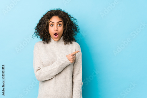 Young african american curly hair woman pointing to the side © Asier