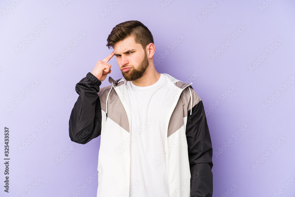 Naklejka premium Young man isolated on purple background pointing temple with finger, thinking, focused on a task.