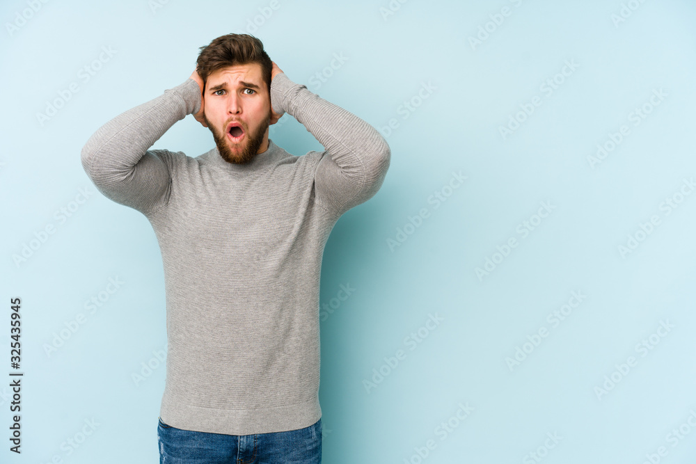 Young caucasian man isolated on blue background being shocked, she has remembered important meeting. Young caucasian man isolated on blue background being shocked, she has remembered important meeting.