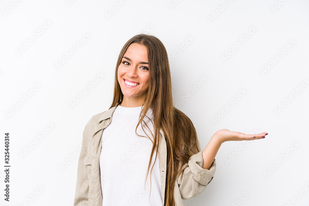 Young caucasian woman isolated showing a copy space on a palm and holding another hand on waist. Young caucasian woman isolated showing a copy space on a palm and holding another hand on waist.