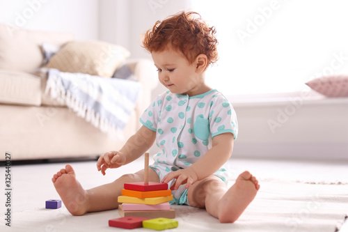 Cute little child playing with toy on floor at home