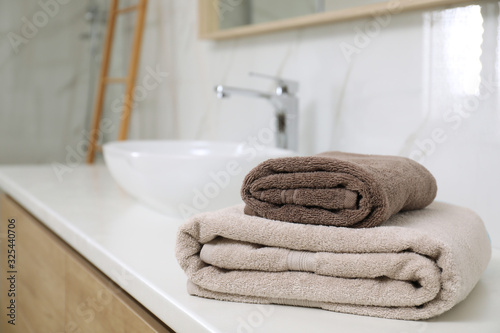 Stack of clean towels on bathroom countertop. Space for text
