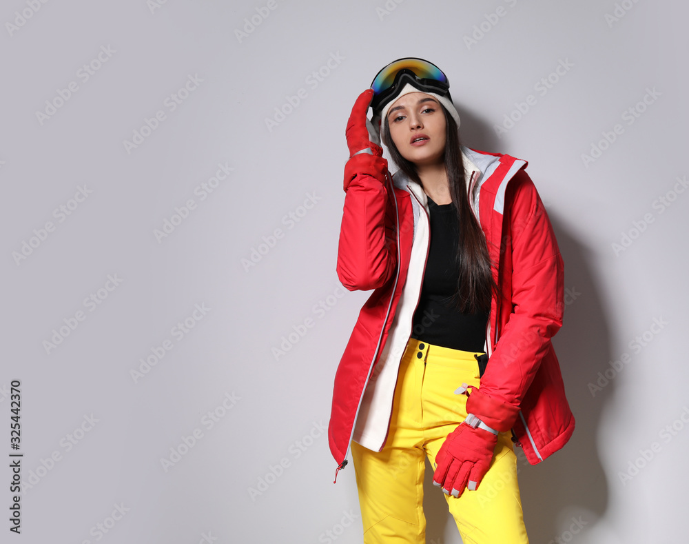 Fototapeta premium Woman wearing stylish winter sport clothes on light grey background