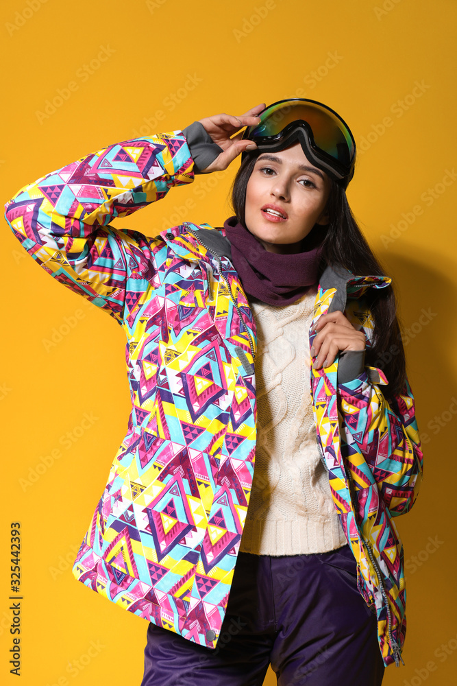 Woman wearing stylish winter sport clothes on yellow background Woman wearing stylish winter sport clothes on yellow background