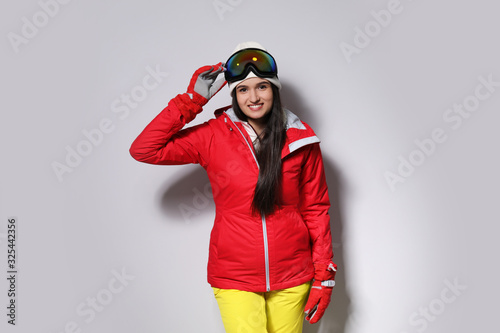 Woman wearing stylish winter sport clothes on light grey background