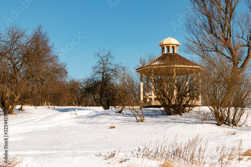 Manor Grebnevo winter gazebo on Bank of Barsky pond at bright Sunny day on natural background photo