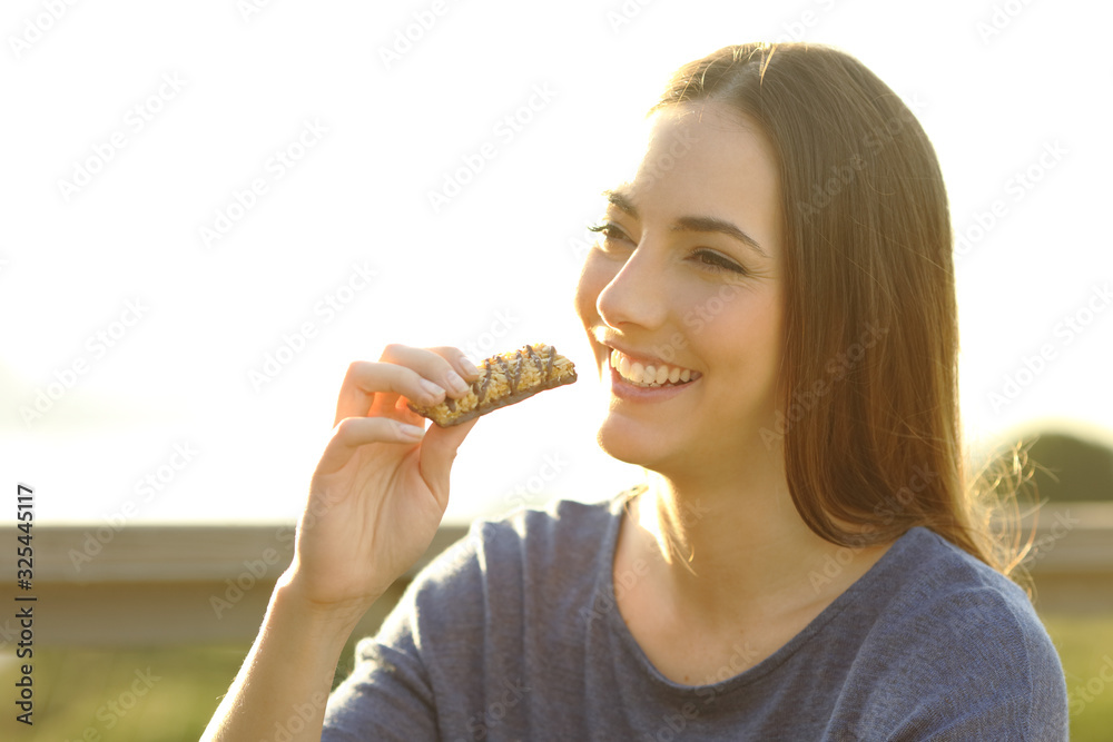 Happy woman is eating a snack outdoors Happy woman is eating a snack outdoors