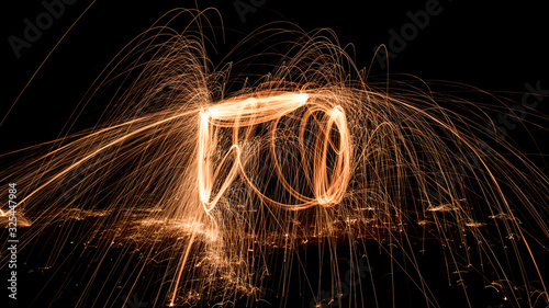Steel wool shower fire and sparks flying in the air at night light art long exposure background