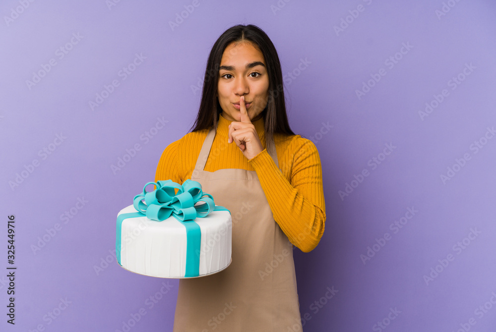 Young asian woman holding a cake isolated keeping a secret or asking for silence. Young asian woman holding a cake isolated keeping a secret or asking for silence.