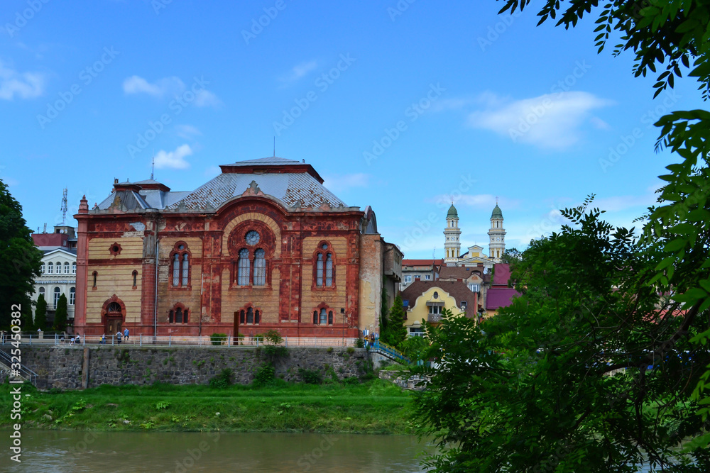 building of the old synagogue on the banks of the river and the bell tower of the Holy Cross Cathedral, Uzhgorod, Ukraine