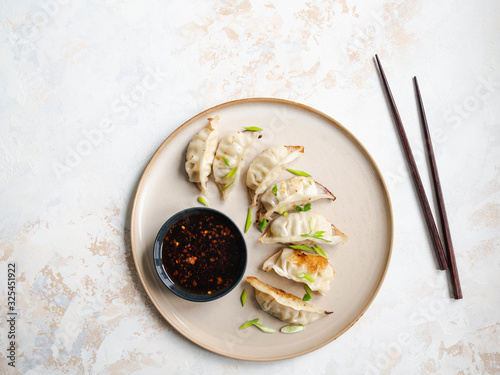 Photos Chinese traditional dumplings - gyoza with pork and vegetables on a round plate with soy sauce in a bowl