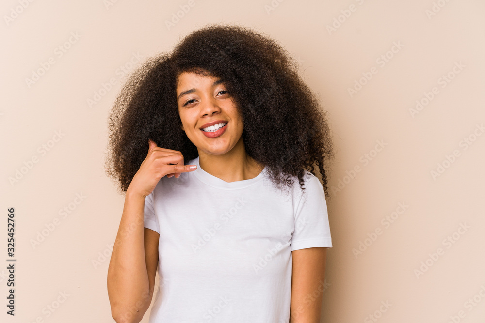 Young african american woman showing a mobile phone call gesture with fingers. Young african american woman showing a mobile phone call gesture with fingers.