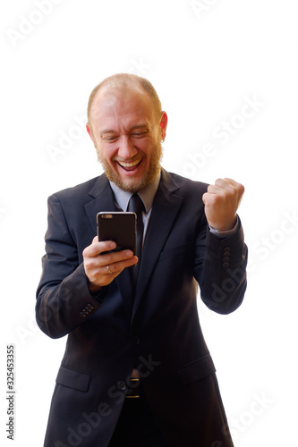 Businessman in a black suit using a mobile phone in order to keep abreast of all the news. Makes the photo on the smartphone, writes notes and e-mails, enjoy chat, add new contacts, and playing games. © YOUproduction