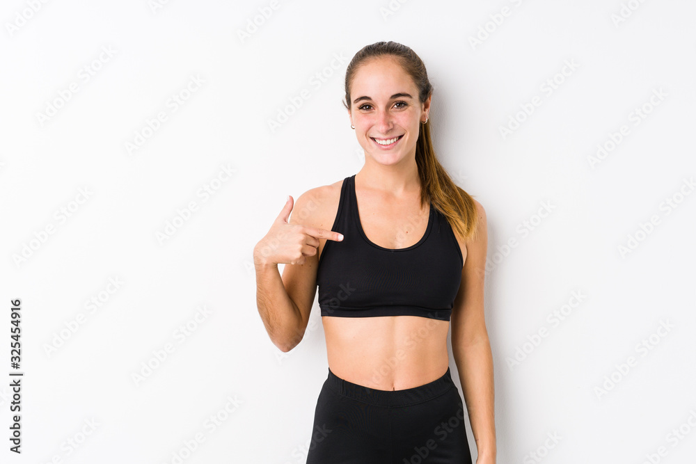 Young caucasian fitness woman posing in a white background person pointing by hand to a shirt copy space, proud and confident Young caucasian fitness woman posing in a white background person pointing by hand to a shirt copy space, proud and confident