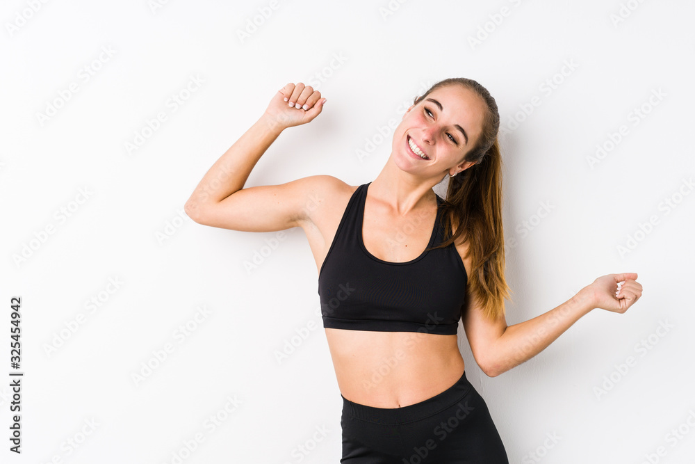Young caucasian fitness woman posing in a white background dancing and having fun. Young caucasian fitness woman posing in a white background dancing and having fun.