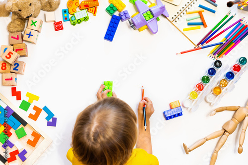 Prescool boy drawing on floor on paper. Kid play with blocks, plane and cars. photo