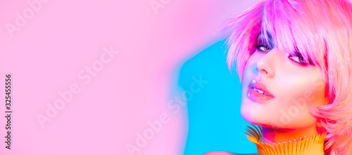 Fashion model woman in colorful bright lights, portrait of beautiful party girl with trendy make-up and haircut. Art design of disco dancer, colorful make up. On colourful vivid background. Pink hair