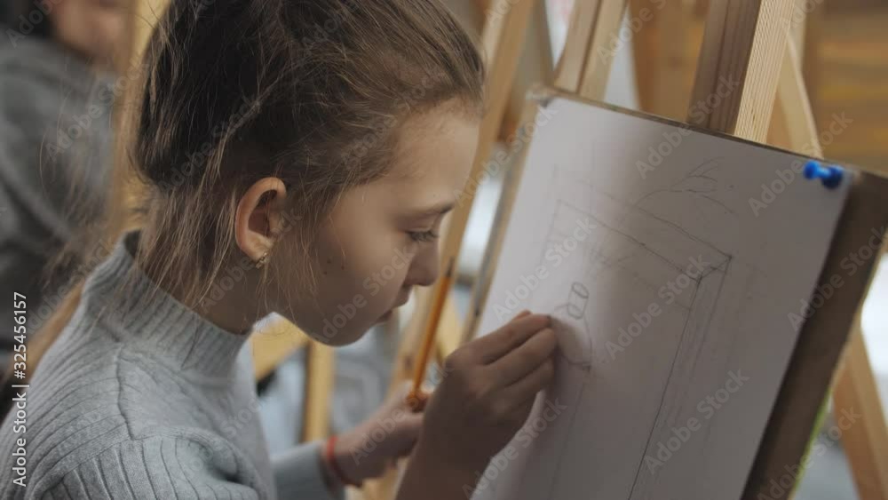 The girl in the drawing school learn to draw still life. Close-up of girl making sketches with a pencil on a sheet of paper.