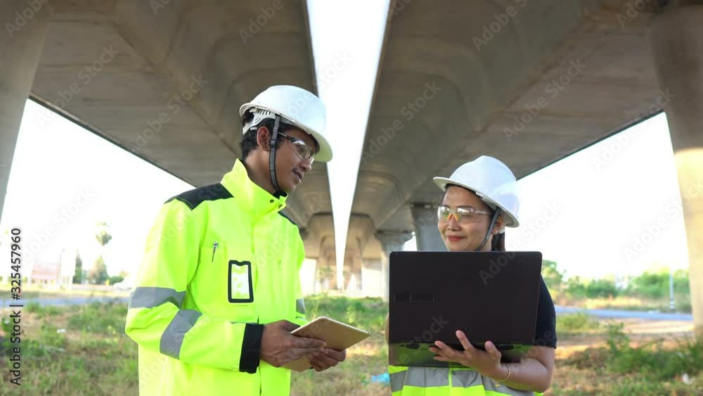 Two engineers discuss about work at the site of large bridge under construction,Management consulting people discussion with engineers about the progress and construction planning of highway