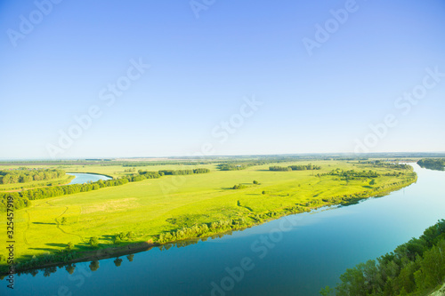 Full-flowing flat river on a warm summer evening in the light of the setting sun