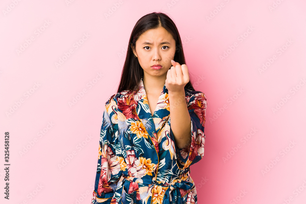 Young chinese woman wearing a kimono pajama isolated showing fist to camera, aggressive facial expression. Young chinese woman wearing a kimono pajama isolated showing fist to camera, aggressive facial expression.