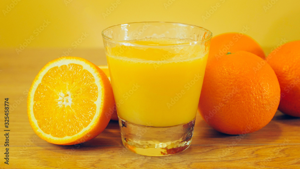 Freshly squeezed orange juice in glass, close-up. Glass of orange juice on wooden and yellow background. Orange juice, healthy, organic drink. Glass of orange juice and orange slices. Freshly squeezed orange juice in glass, close-up. Glass of orange juice on wooden and yellow background. Orange juice, healthy, organic drink. Glass of orange juice and orange slices.