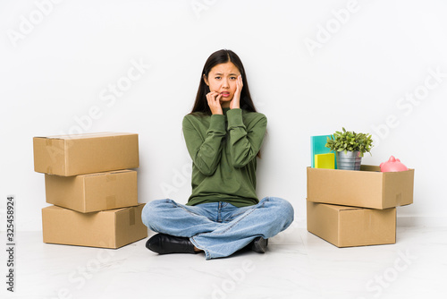 Young chinese woman moving to a new home whining and crying disconsolately. photo