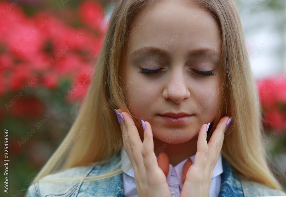 Young girl with long white hair in a denim jacket walks in the garden with blooming azalea Young girl with long white hair in a denim jacket walks in the garden with blooming azalea