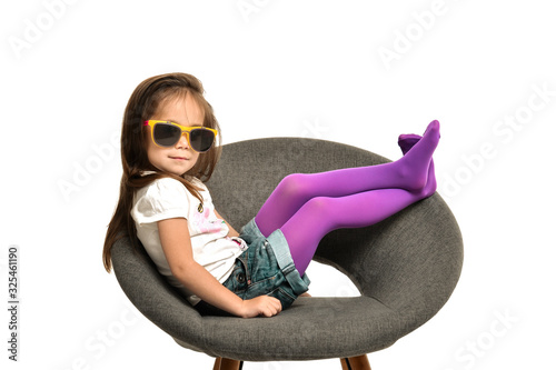 stylish toddler girl with glasses in a chair
