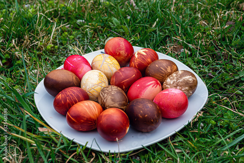 White plate with colored easter eggs in green grass