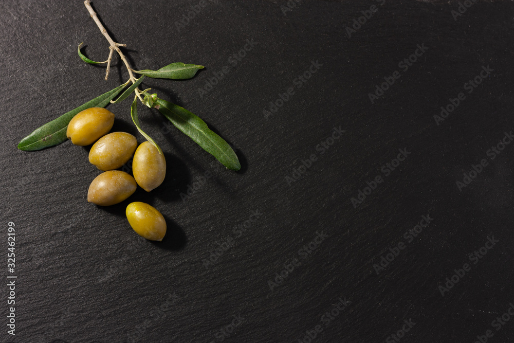 Olives and an olive branch with leaves on black background for copy ...