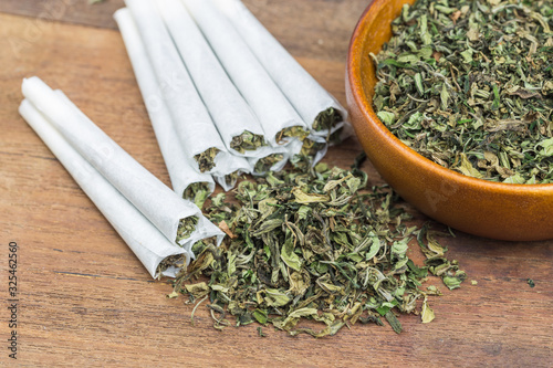 Marijuana on wooden bowl and hashish joint rolling for smoking.