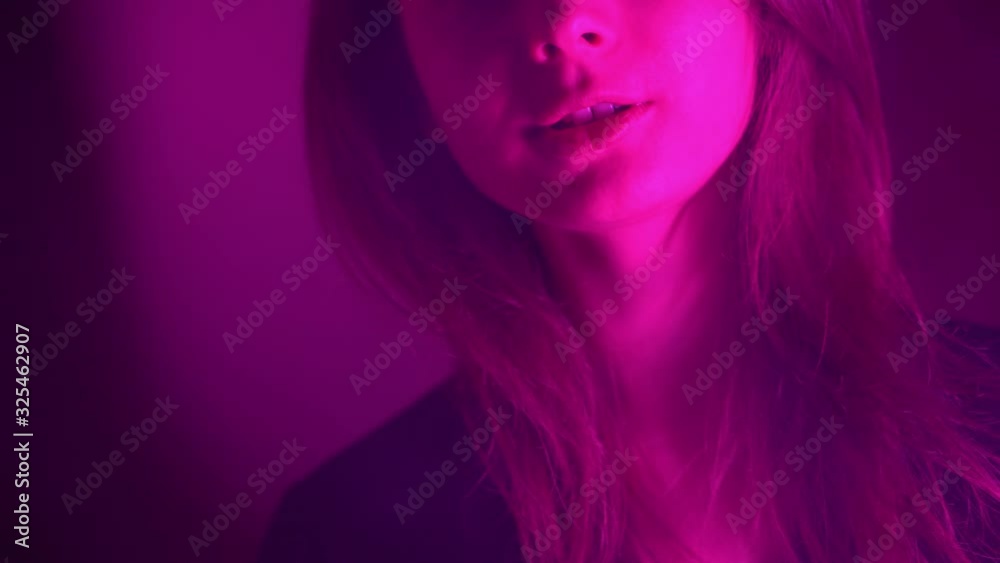 Beautiful, young, hookah-Smoking woman. An attractive girl smokes flavored tobacco. Breathe out the smoke in the neon light Beautiful, young, hookah-Smoking woman. An attractive girl smokes flavored tobacco. Breathe out the smoke in the neon light