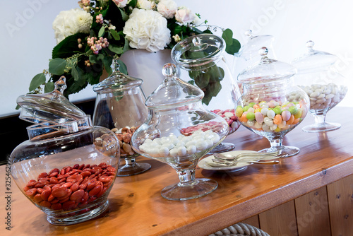 Table with glass jars with assortment of colored sugared almonds