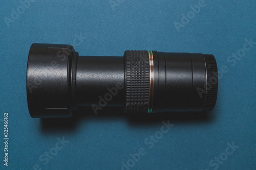 top view of a black zoom lens for a camera on a blue background