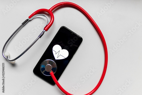 Schwarzes Smartphone mit Herzsymbol und Herzschlag und Stethoskop zeigen digitale Patientenakte, digitale Gesundheitsprogramme und Fitnesstracker in der modernen Gesundheitspraxis photo