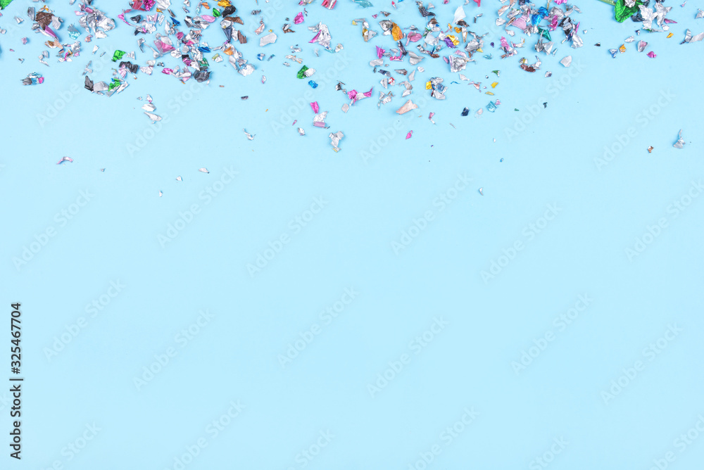 Multicolored confetti on blue background. Flat lay, top view.