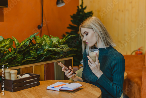 beautiful blrndinka woman in business casual style while working in a cafe and restaurant coffee.lifestyle woman on the phone drinking coffee text message on smartphone app.attractive girl with a note © Асель Иржанова