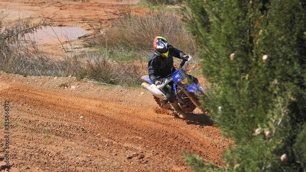 Zoom photo of unidentified motocross rider performing extreme stunts in off road dirt track Zoom photo of unidentified motocross rider performing extreme stunts in off road dirt track