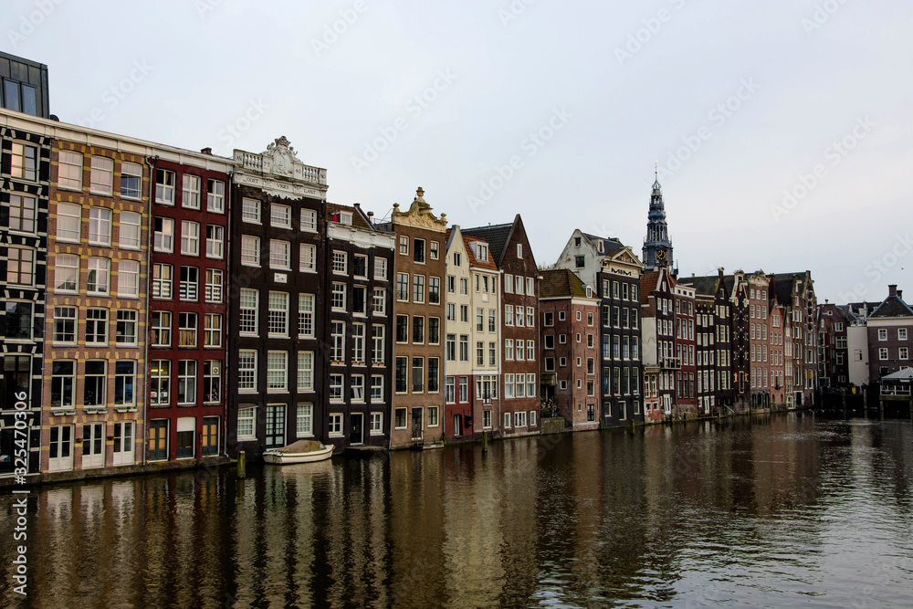 Cityscape of Amsterdam. Dutch city architecture. Modern exterior of buildings. Reflection in water of canal.