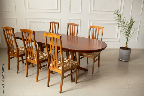 A classic set of wooden furniture for the kitchen. A set of chairs to the table in a classic interior