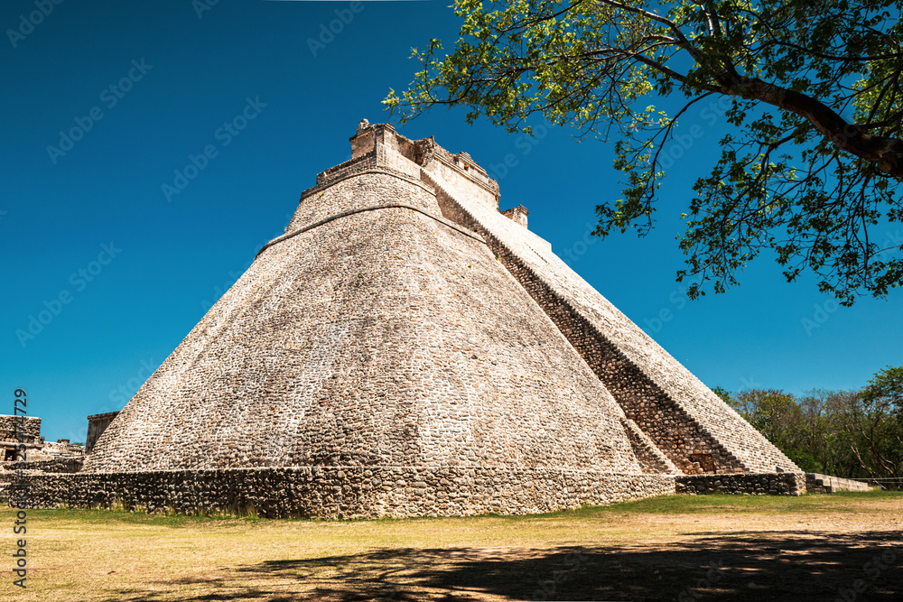 Side view of the Pytamid of the Magician in an ancient Maya city of Uxmal, Yucatán, Mexico against the backdrop of a deep blue sky.