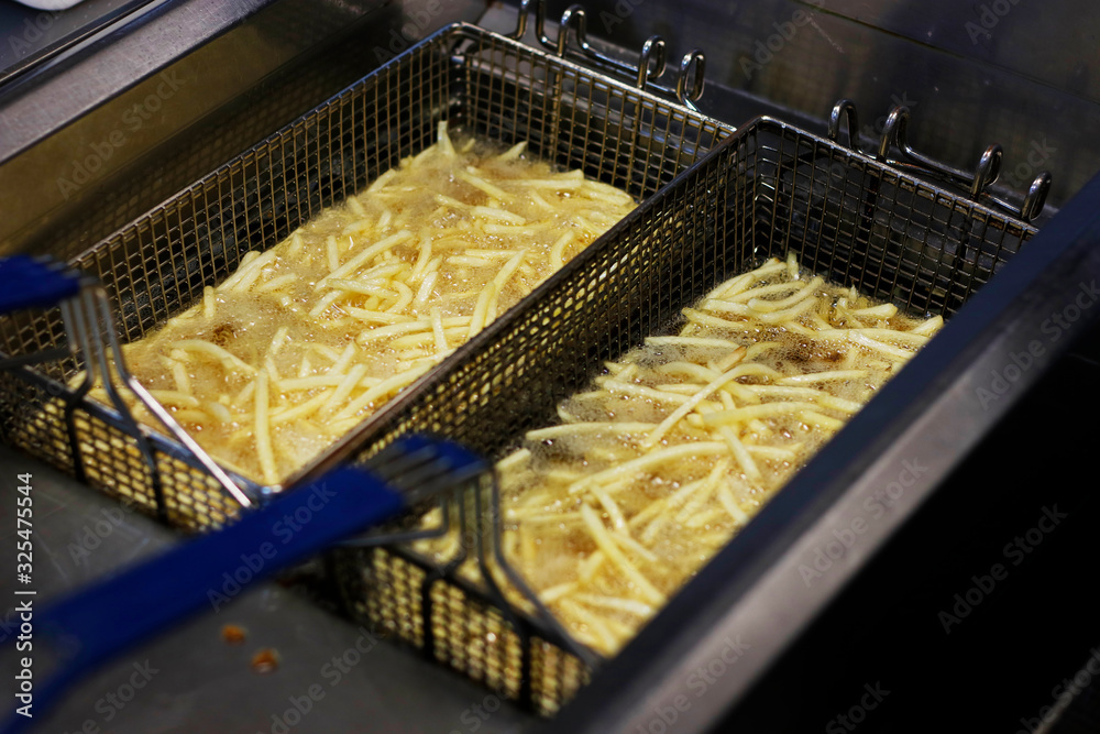 Cooking french fries. Close up of Frying french fries in the fryer in hot oil