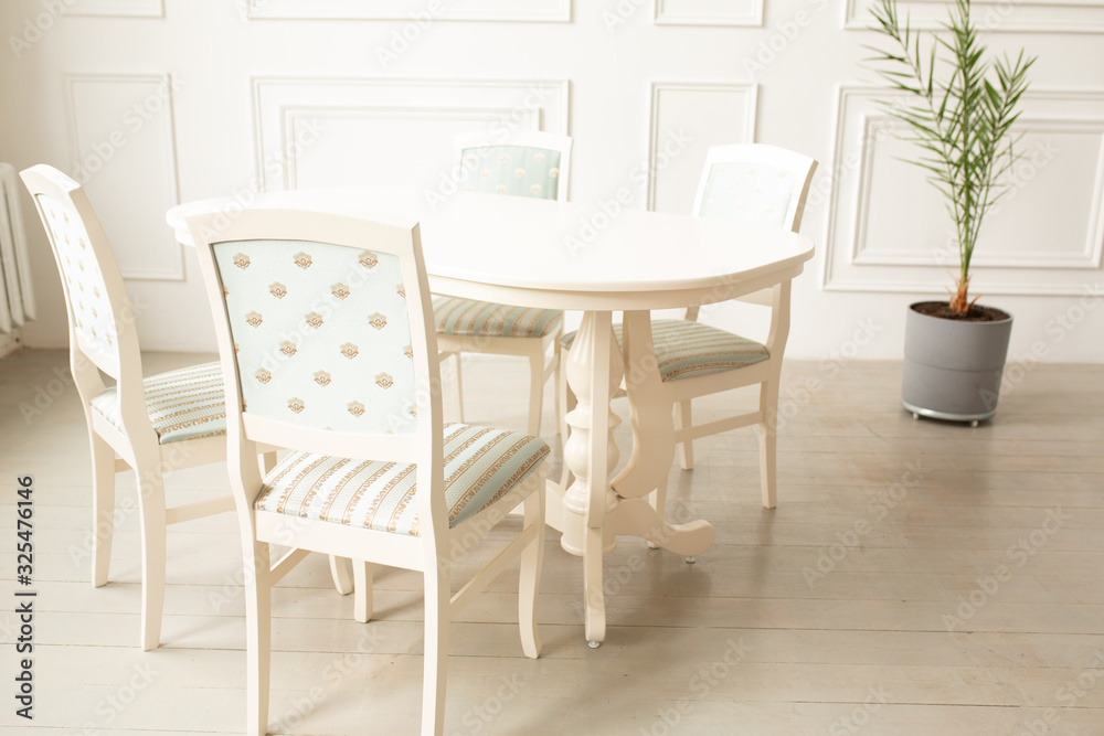 White tables and chairs for dinner in a classic interior. Upholstered chairs for comfortable sitting at the table